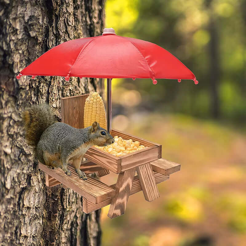 Squirrel enjoying food at a wooden hanging feeding table with a red umbrella outdoors.